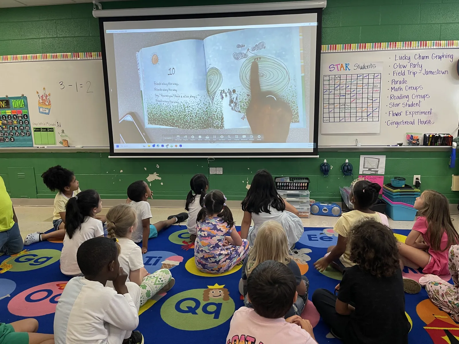 Students sit on the classroom rug watching a Strolling Adventure page on the projector