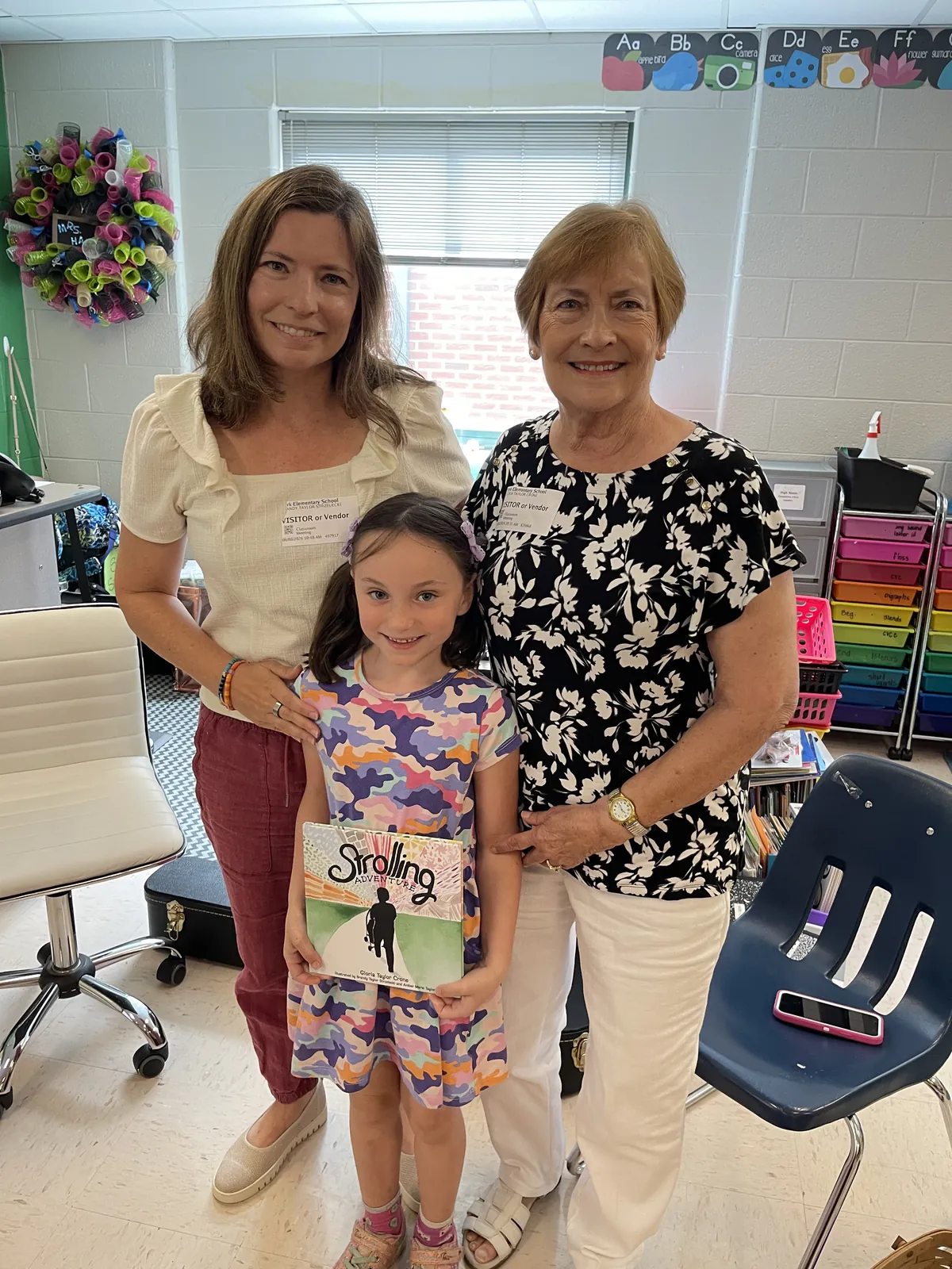 Gloria Taylor Crone and Brandy Taylor Strzelecki with a student holding a copy of Strolling Adventure